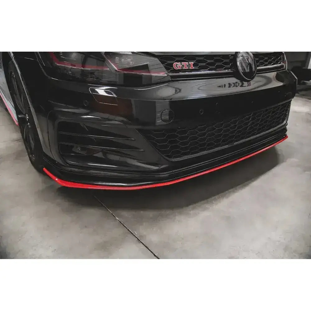 Frontspoiler VW Golf 7 GTI TCR med rød stripe nederst, sett forfra i skrå vinkel på betonggulv.