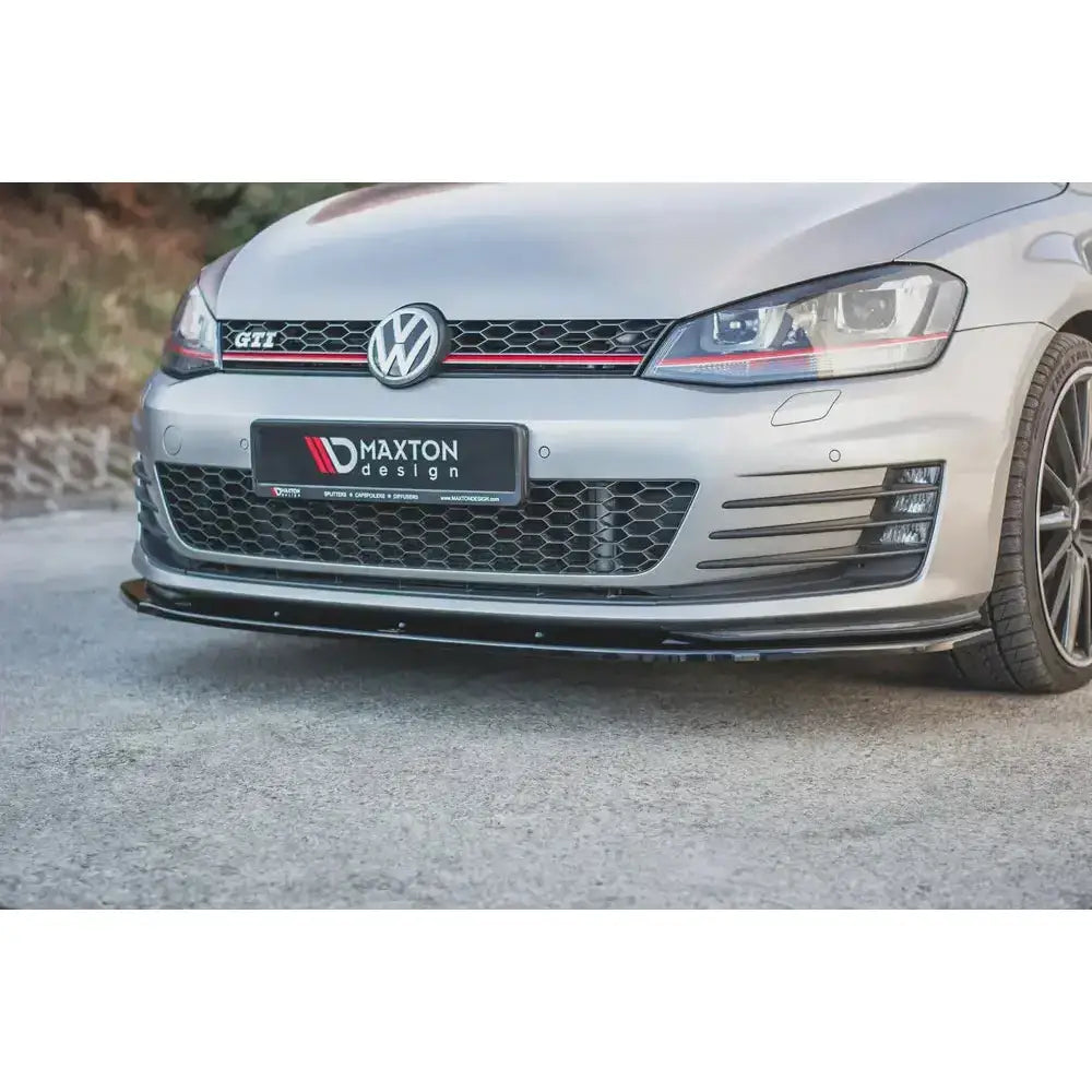 Spoiler til VW Golf VII GTI, svart frontsplitter montert på sølv bil med bikubemønstret grill.