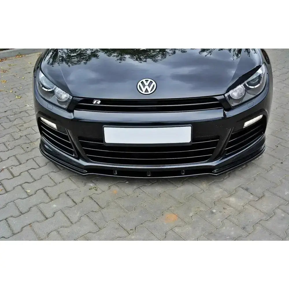 Front lip på VW Scirocco R 08-14, sort frontspoiler sett forfra og nedenfra mot gatebelagt bakgrunn.