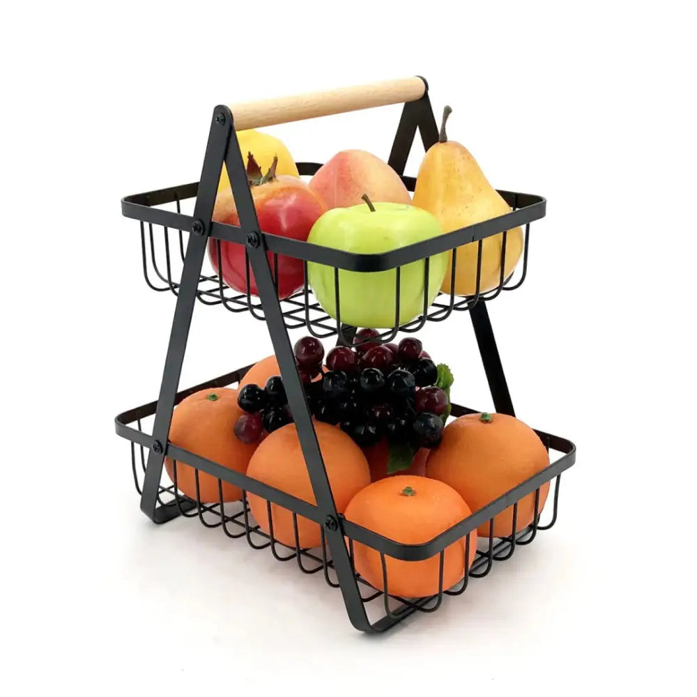 Fruktkurv med flere nivåer i sort metall, trehåndtak og fylt med assortert fersk frukt, sett på skrå.