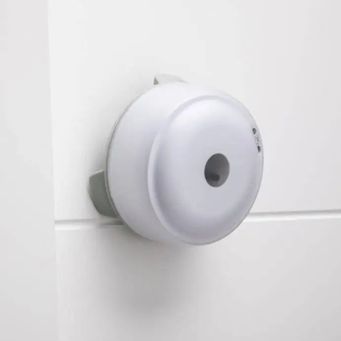 Reaksjonslys sett, sidevisning av hvit rund sensor montert på vegg med synlig hull i midten og enkel design.