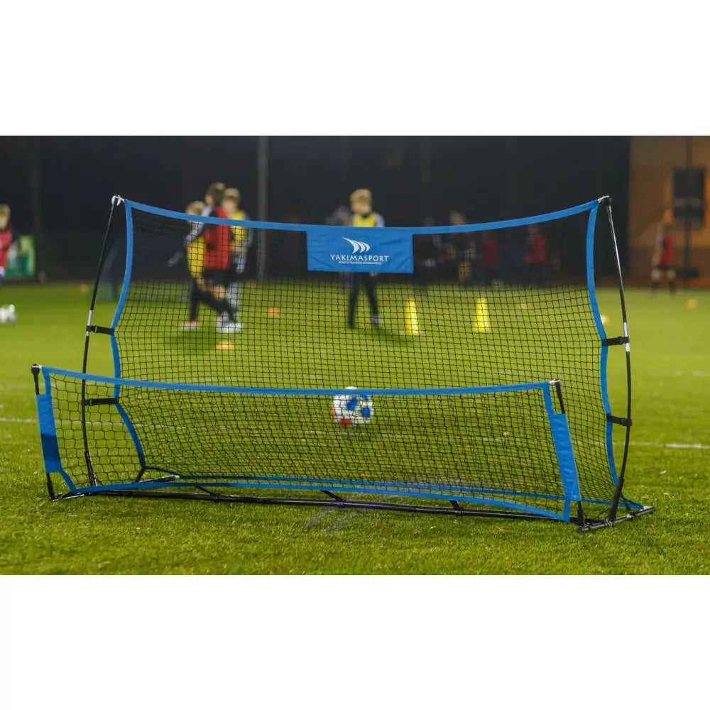 Galaktisk Hoppeseng, sort og blått treningsnett plassert på gressbane med folk og kjegler i bakgrunnen.