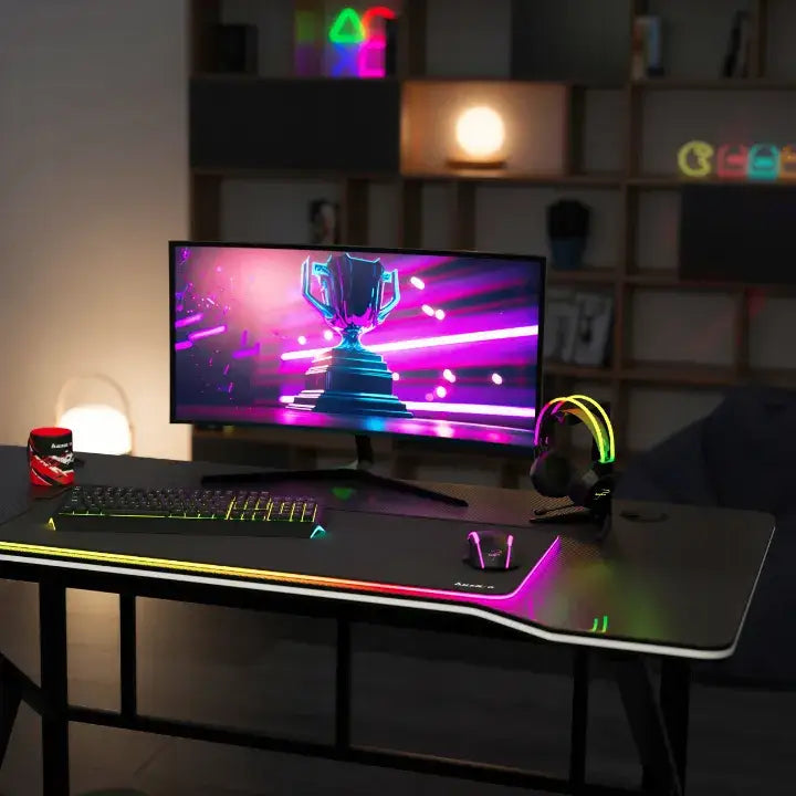 Gamingbord Huzaro Hero 1.6, frontvisning med RGB-lys, stor buet skjerm, tastatur og rød kopp i mørkt rom.