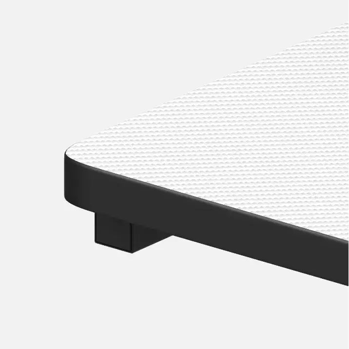 Gamingbord Huzaro Hero 5.0, nærbilde av hvitt hjørne med sort ramme og bein, sett fra skrå vinkel.