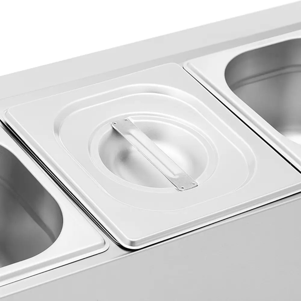 Gårdsregal med seks GN 1/6 beholdere, lokk og håndtak, sett skrått ovenfra med blank finish.