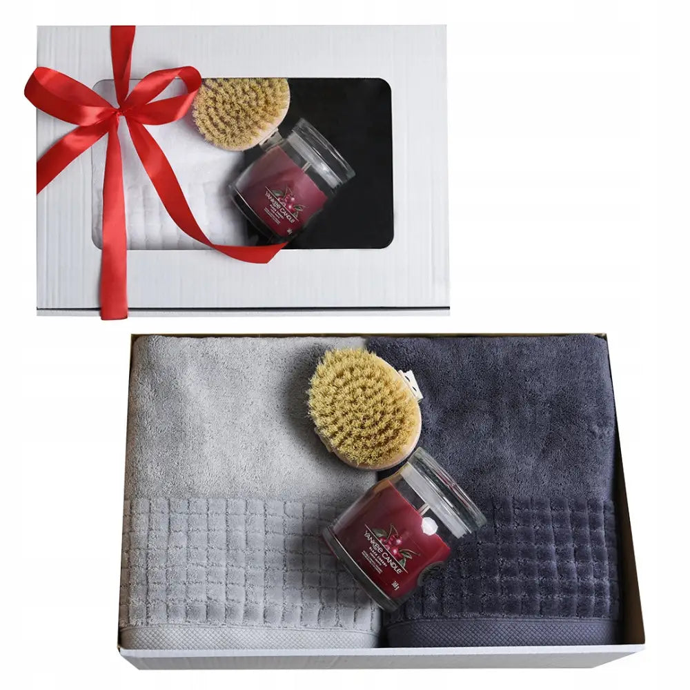 Gavepakke for par med grå og mørkeblå håndklær, natursvamp og rødt duftlys i glass, pyntet med rød sløyfe.