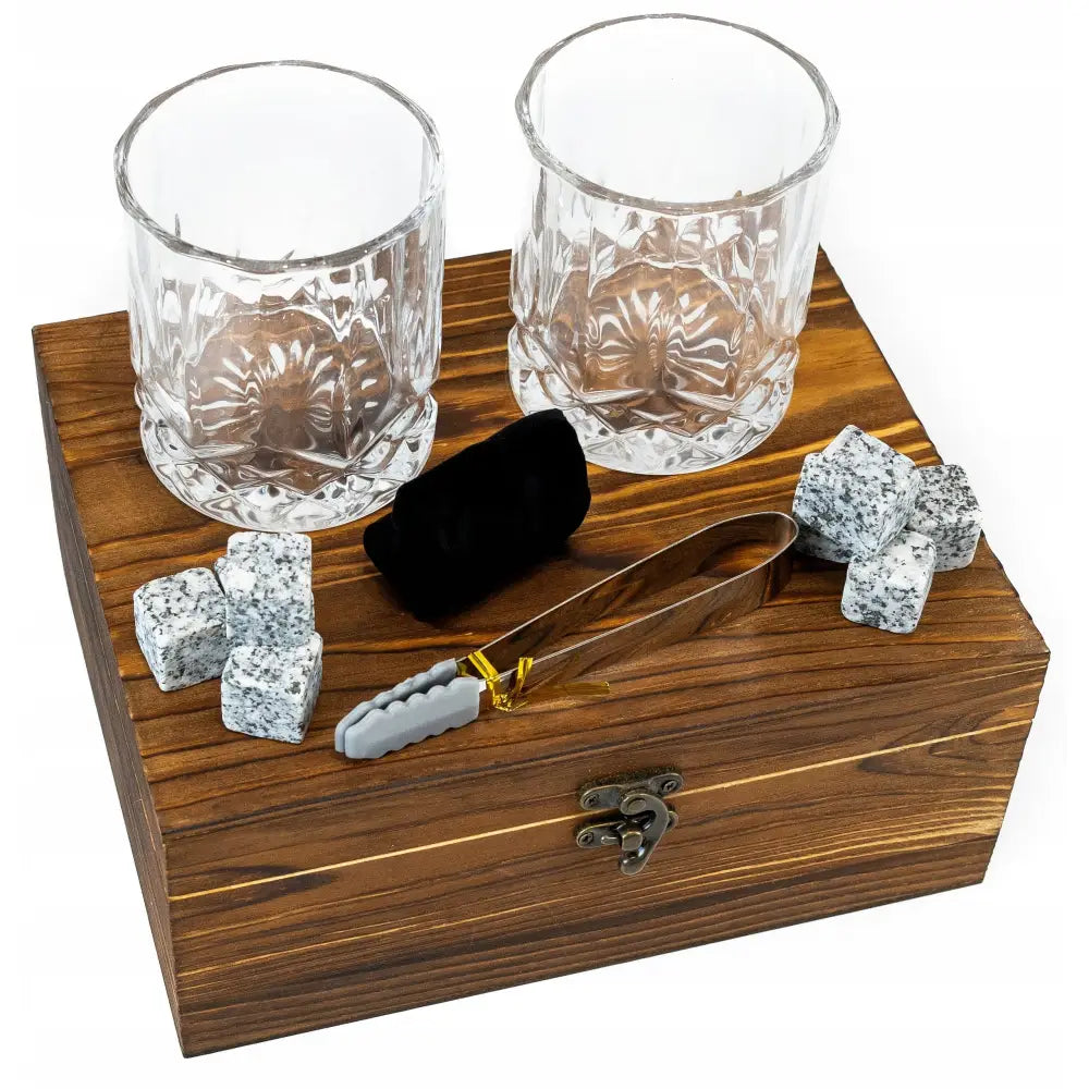 Gavepakke for whisky med to fasettslipte glass, grå steinisterninger, metalltang og svart fløyelspose på treboks.