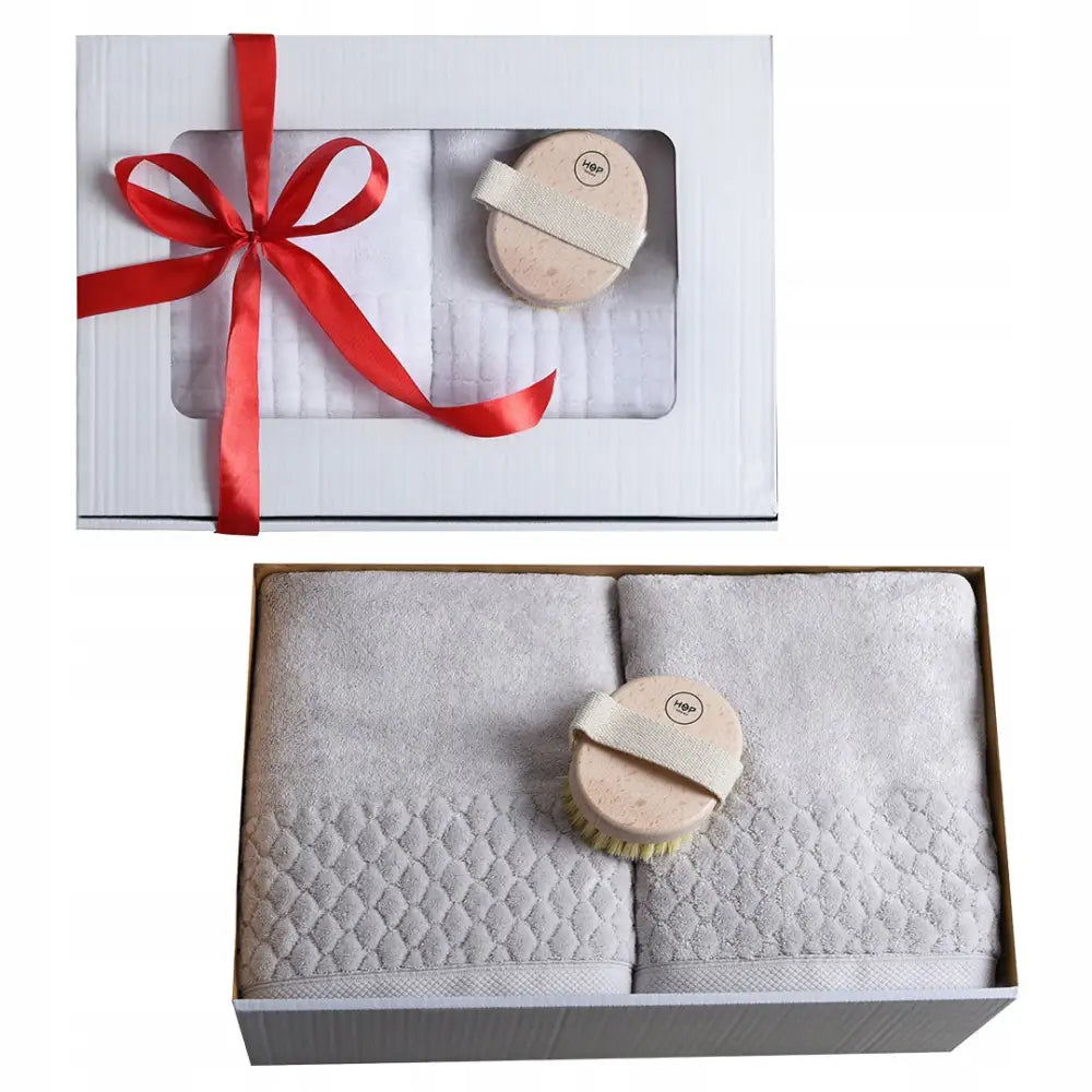Gavesett for henne med to lysegrå mønstrede håndklær og oval massasjebørste i gaveeske med rødt bånd.