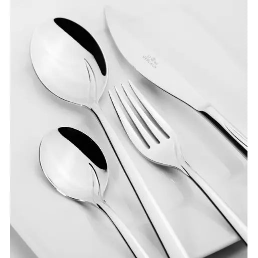 Gerlach Flames bestikksett, sett ovenfra med kniv, gaffel, spiseskje og teskje på hvite tallerkener.