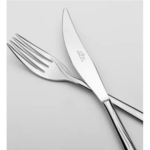 Gerlach Flames bestikk, gaffel og kniv i blankt stål med synlig gravering, skrå vinkel mot lys bakgrunn.