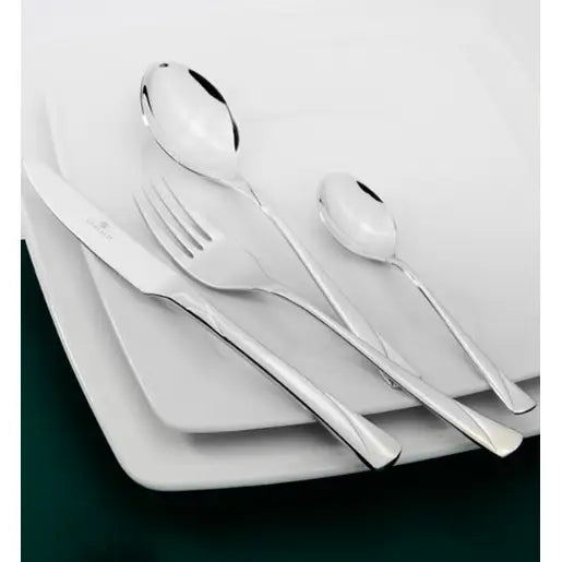 Gerlach Valor bestikk, fire blanke deler i rustfritt stål diagonalt på hvite tallerkener, sett ovenfra.