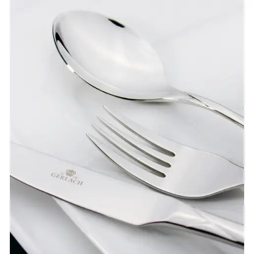 Gerlach Valor bestikksett, sett ovenfra med skje, gaffel og kniv på hvite tallerkener, blank finish.