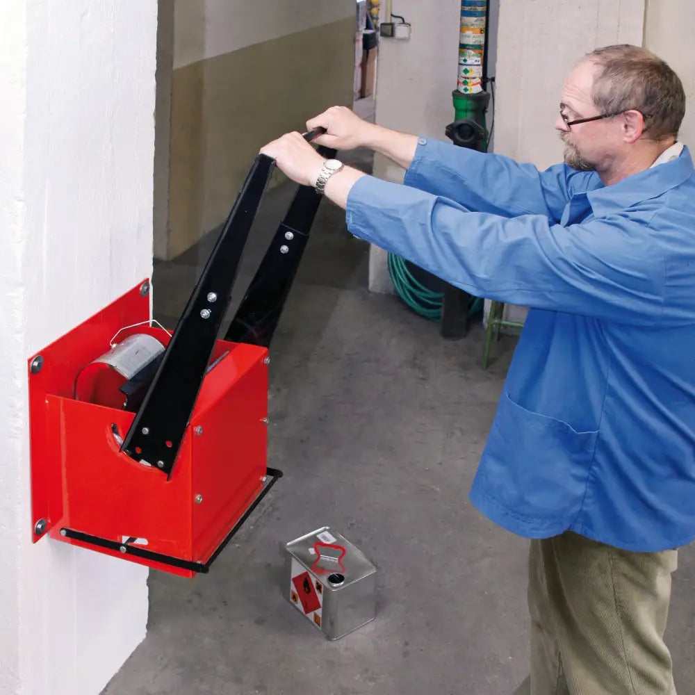 Gjenvinningspresse til store metallbokser, sidevisning i bruk med sort håndtak og metallkanne under.