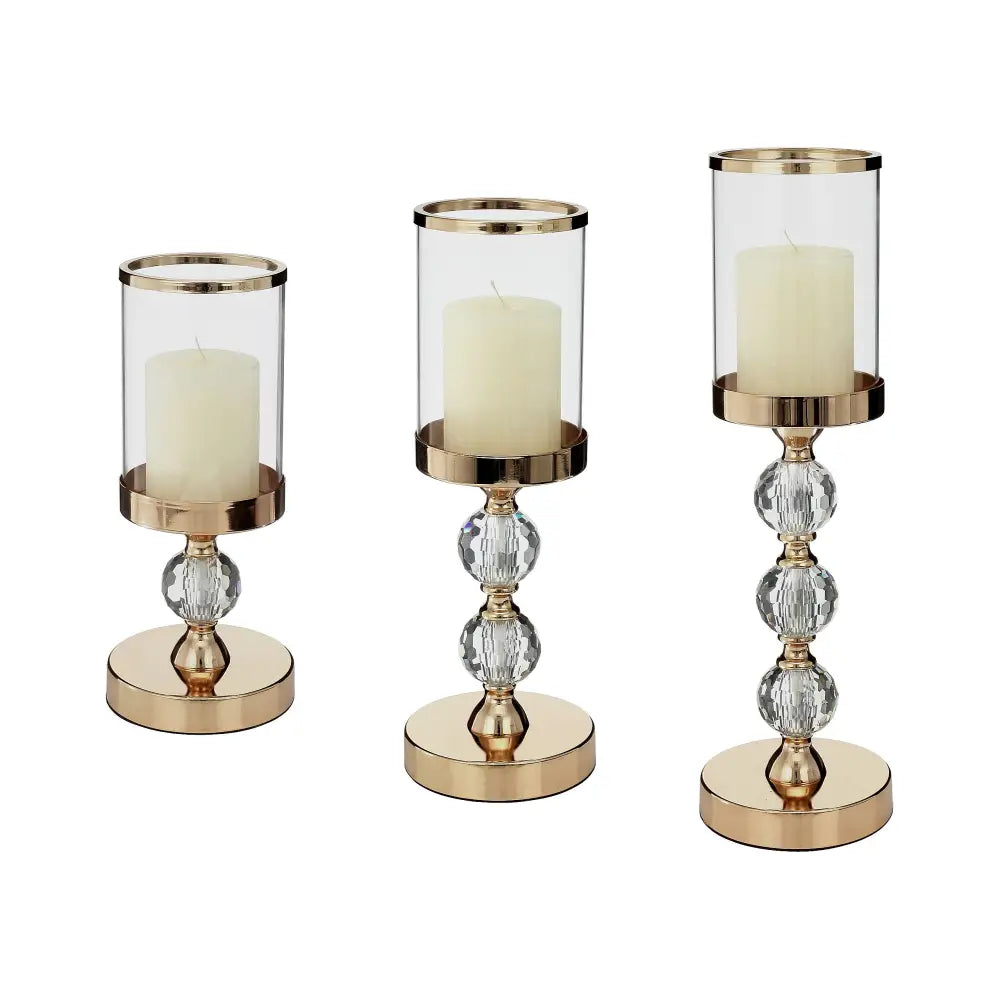 Glamour lysestake lanterne sett med tre gullbaser, sylindrisk glass og fasetterte krystallkuler, hvite blokklys.