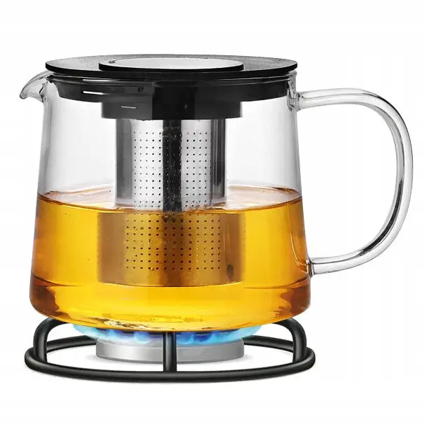 Glasskanne med tebrygger, sett fra siden på stativ med blå flamme og varm te i metallfilteret.