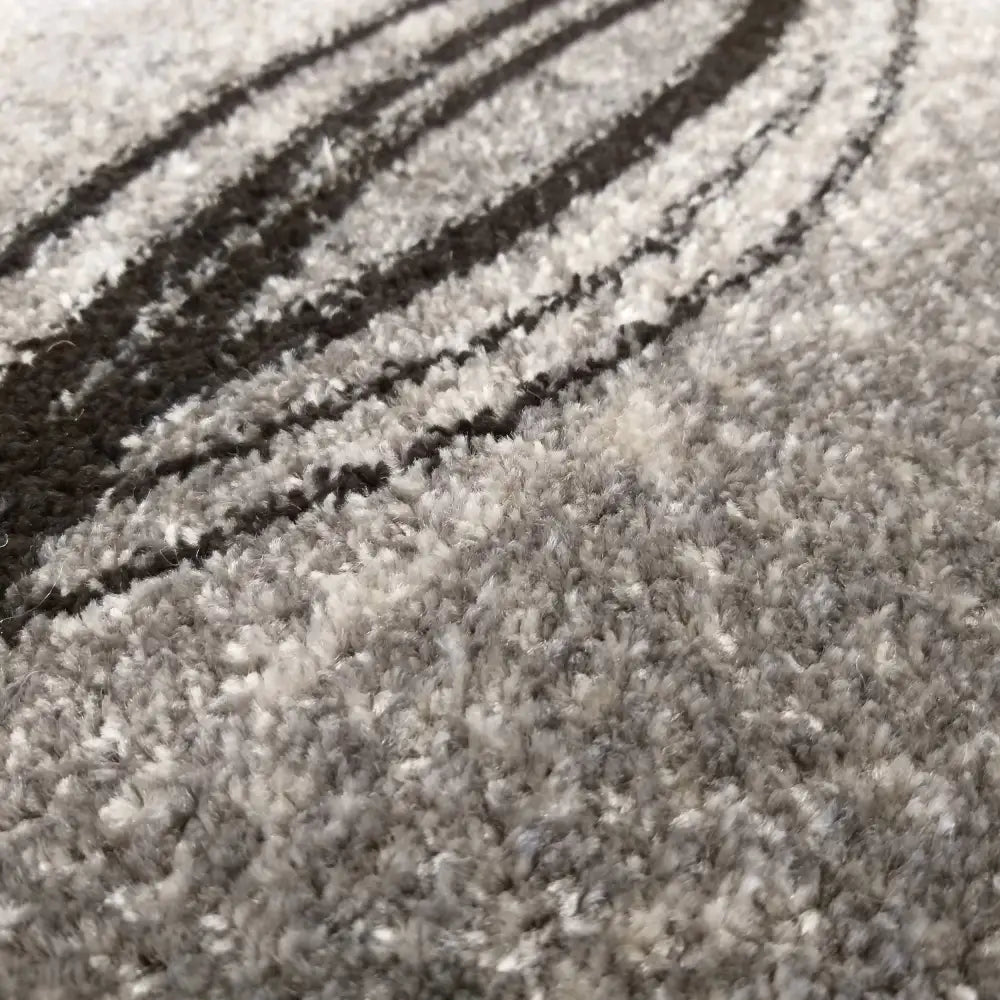 Grått moderne teppe, nærbilde av myk tekstur og mørke buede linjer i det detaljerte fibermønsteret.