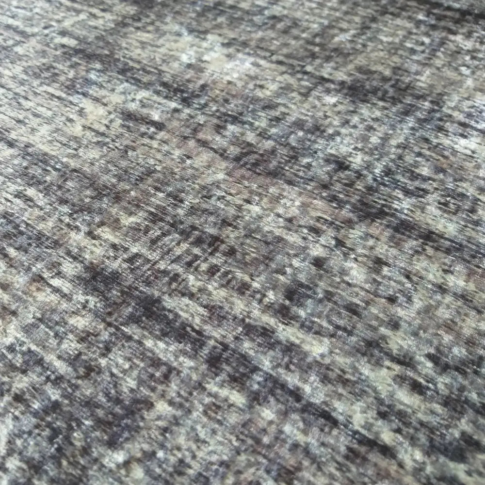 Grå teppe i polyester, nærbilde som fremhever melert veving og struktur i grå, brune og beige nyanser.