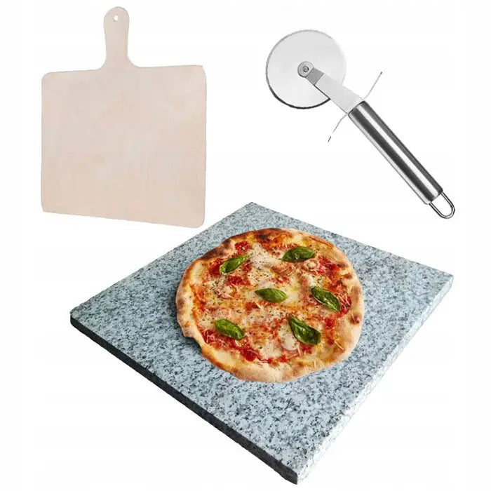 Granitt pizzasteinsett med stekt pizza, lyst pizzabrett og metall pizzahjul vist fra skrå vinkel.