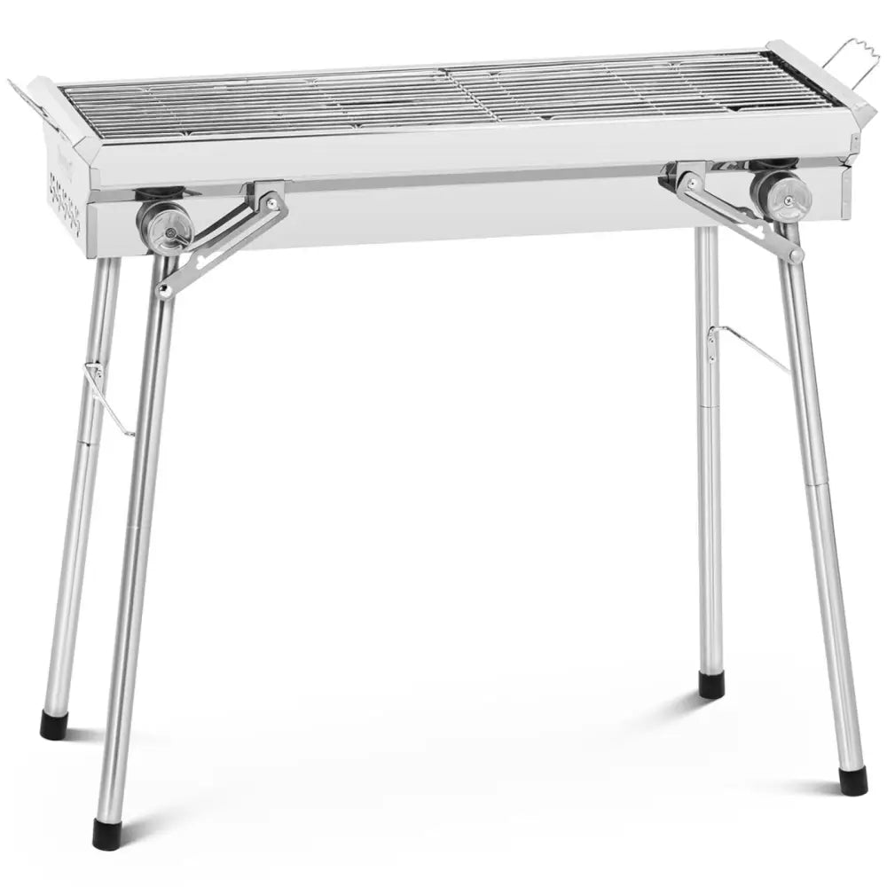 Grill i rustfritt stål med sammenleggbar rist, sett skrått forfra, viser sorte gummiføtter og ben.