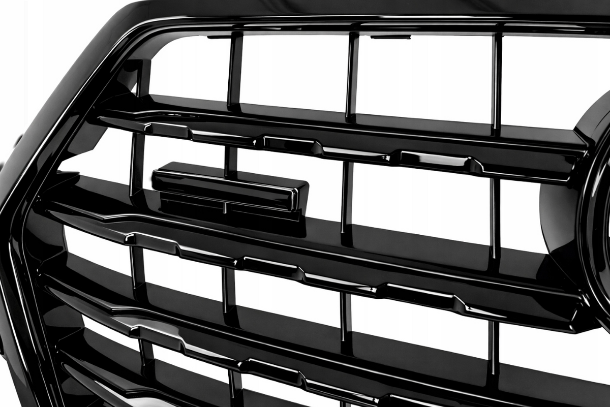 Detaljbilde av S-Line grill til Audi Q7 4M, blank sort lamellstruktur og emblem-festepunkt.