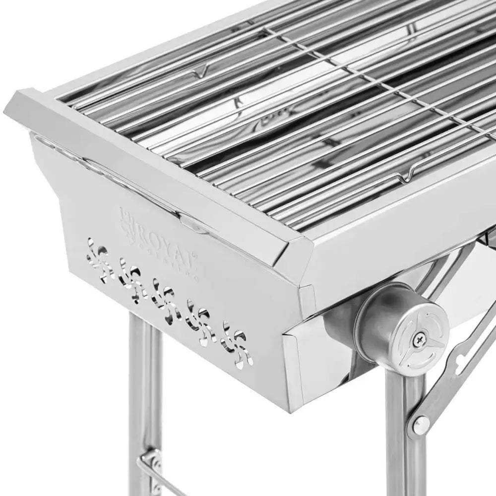 Bærbar kullgrill i rustfritt stål, sidevisning med ventilasjonshull, grillrist og justeringshjul på stativet.