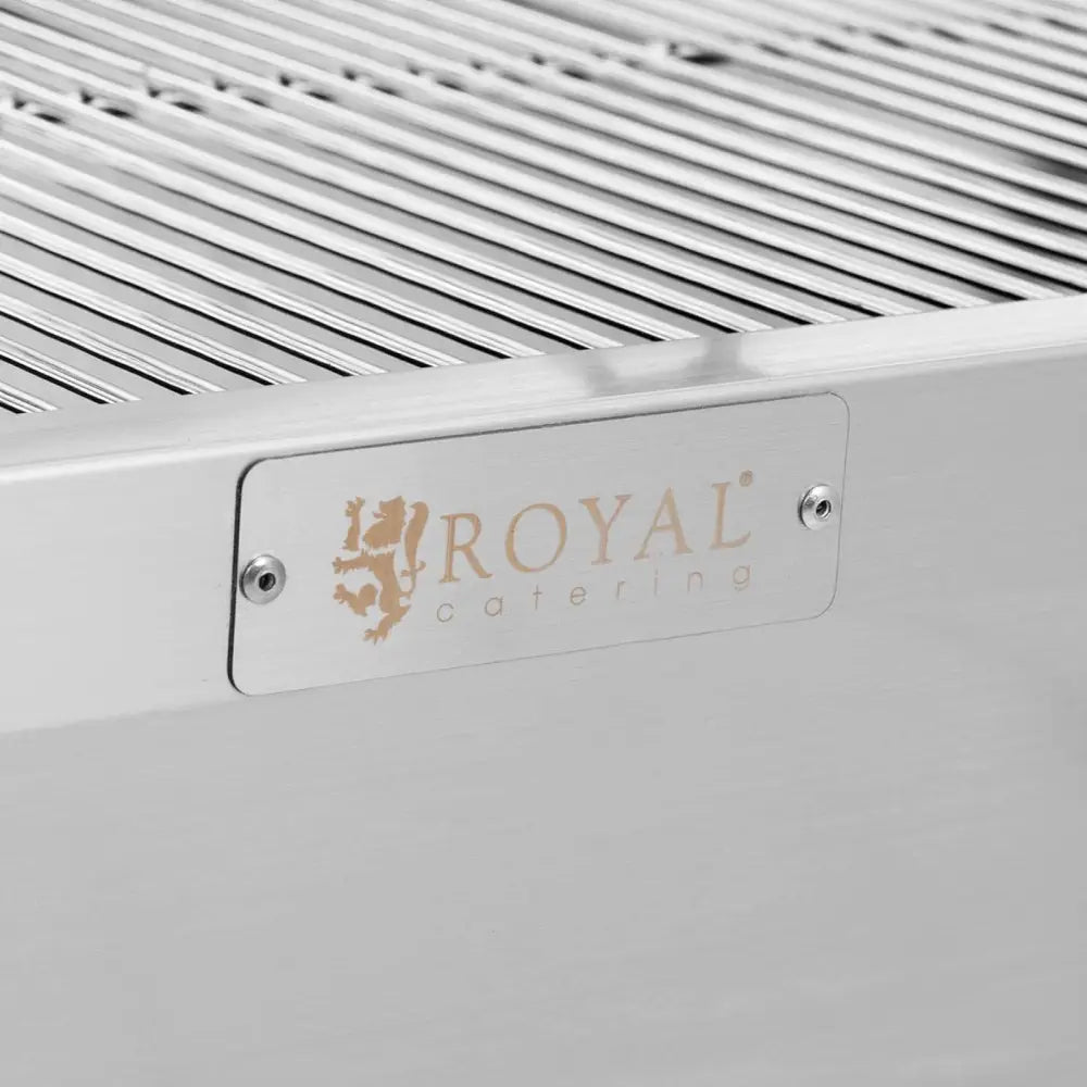 Grillkullgrill, nærbilde av rustfritt stål med riller og metallplate med inngravert logo festet med skruer.