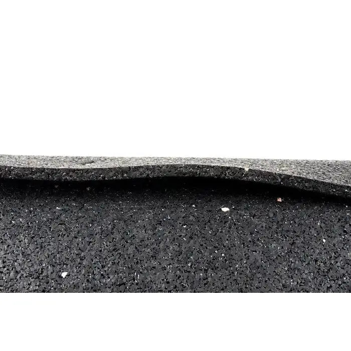 Gulvmatte i sort gummi, nærbilde av grovkornet struktur og lagdeling, ujevn kant synlig mot hvit bakgrunn.