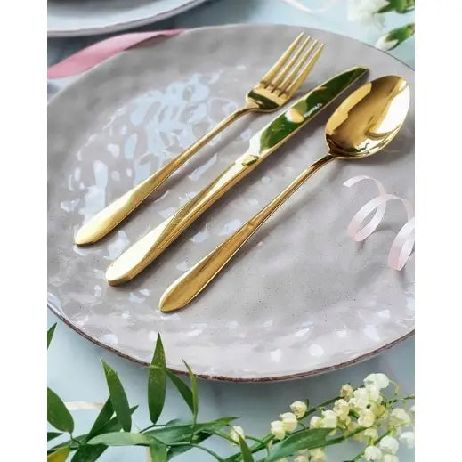 Gylne Bestikk fra Homla, sett for fire, elegant dandert på lys tallerken med blomster og bånd.
