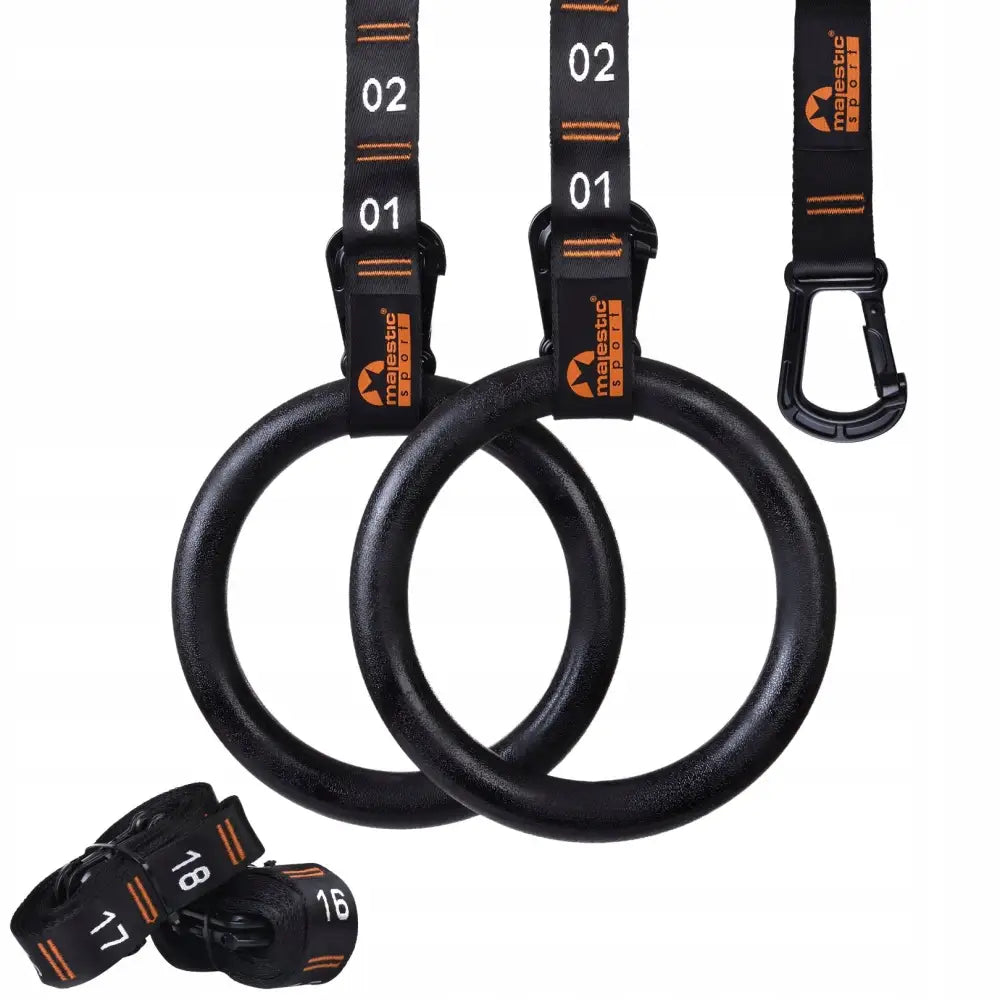 Gymnastikkringer i sort plast med oransje detaljer, justerbare stropper og ekstra stropp med tallmarkeringer.