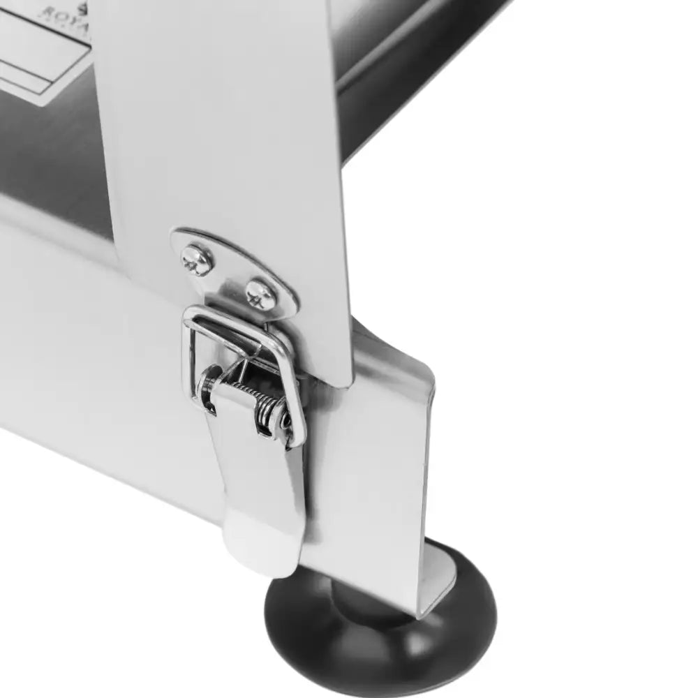 Detalj av håndholdt veg- og fruktskiver, viser metallspenne, skruer og sort gummifot på ståloverflate.