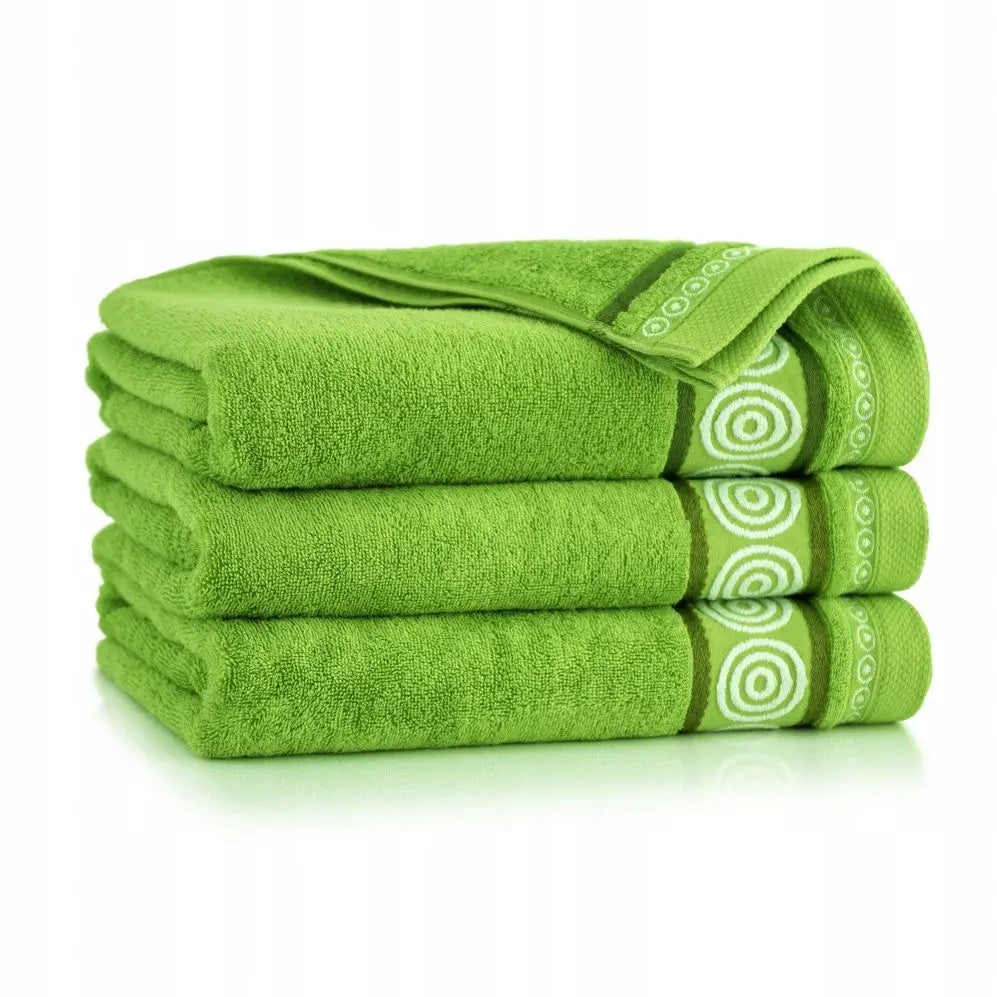 Grønne håndklær i egyptisk bomull, stablet med hvite og grønne sirkelmønstre på kanten, sett fra siden.