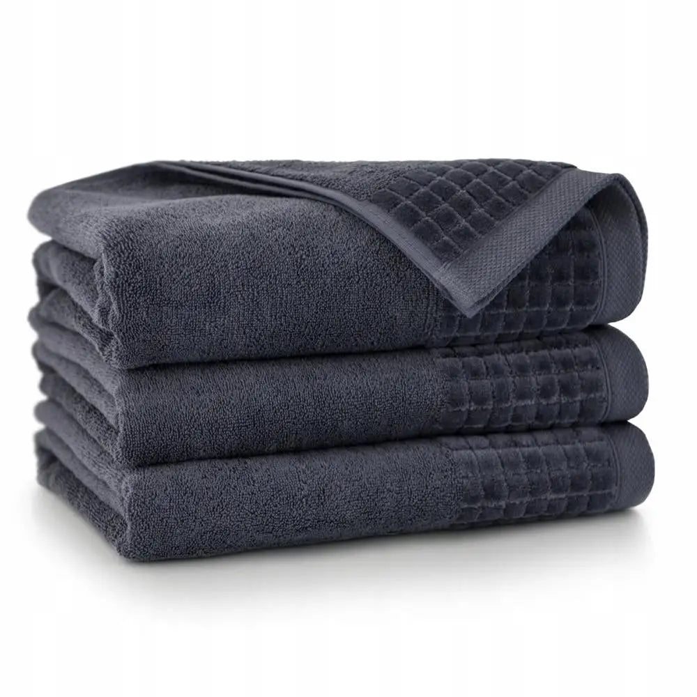 Håndkle Paulo-3 i grafitt-grå, stabel med tre frottéhåndklær og synlig rutemønstret kant.