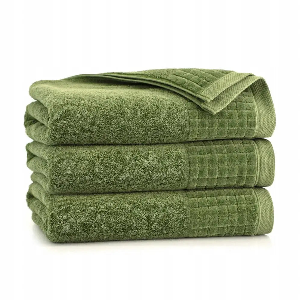 Grønt bomullshåndkle Paulo-3, stablet med synlig rutemønstret kant, sett fra siden.