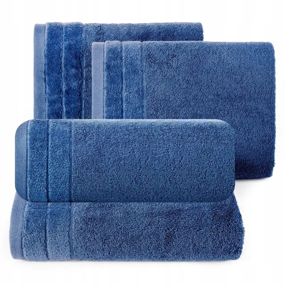 Håndkle sett i marineblå frotté, fire størrelser vist ovenfra med markerte dekorkanter.