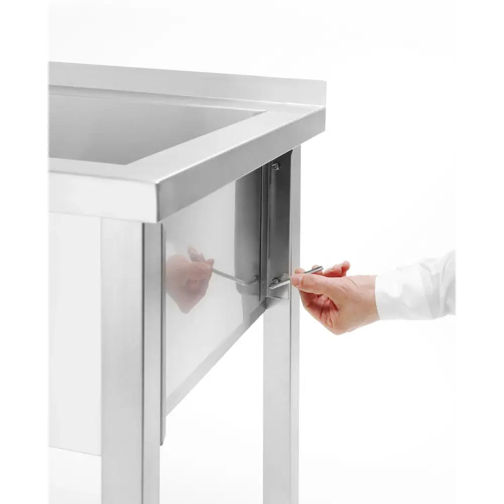 Hendi rustfritt stål gastrovask, nærbilde av montering der en hånd strammer bolt i bordben med unbrakonøkkel.