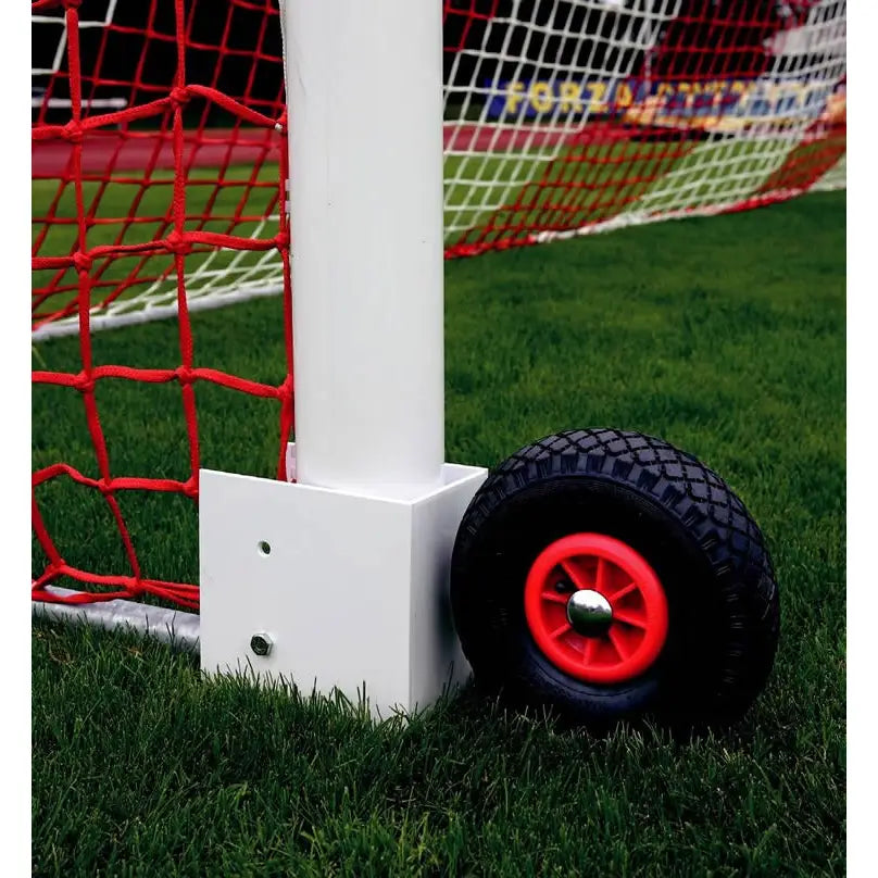 Hjulsett for flyttbare fotballmål, sort og rød gummihjul montert på hvit ramme mot grønt gress.