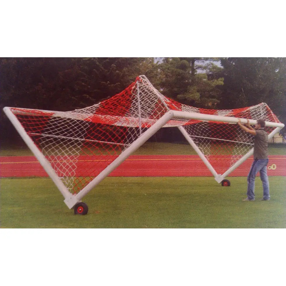 Hjulsett for flyttbare fotballmål, sidevisning mens målet trilles av en person på gress ved løpebane.