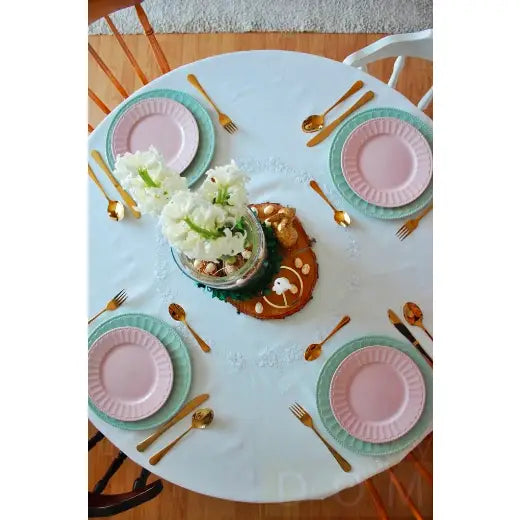 Homla Abele bestikksett, gullfargede gafler, kniver og skjeer dandert på pastellkuverter rundt blomsterpyntet bord.