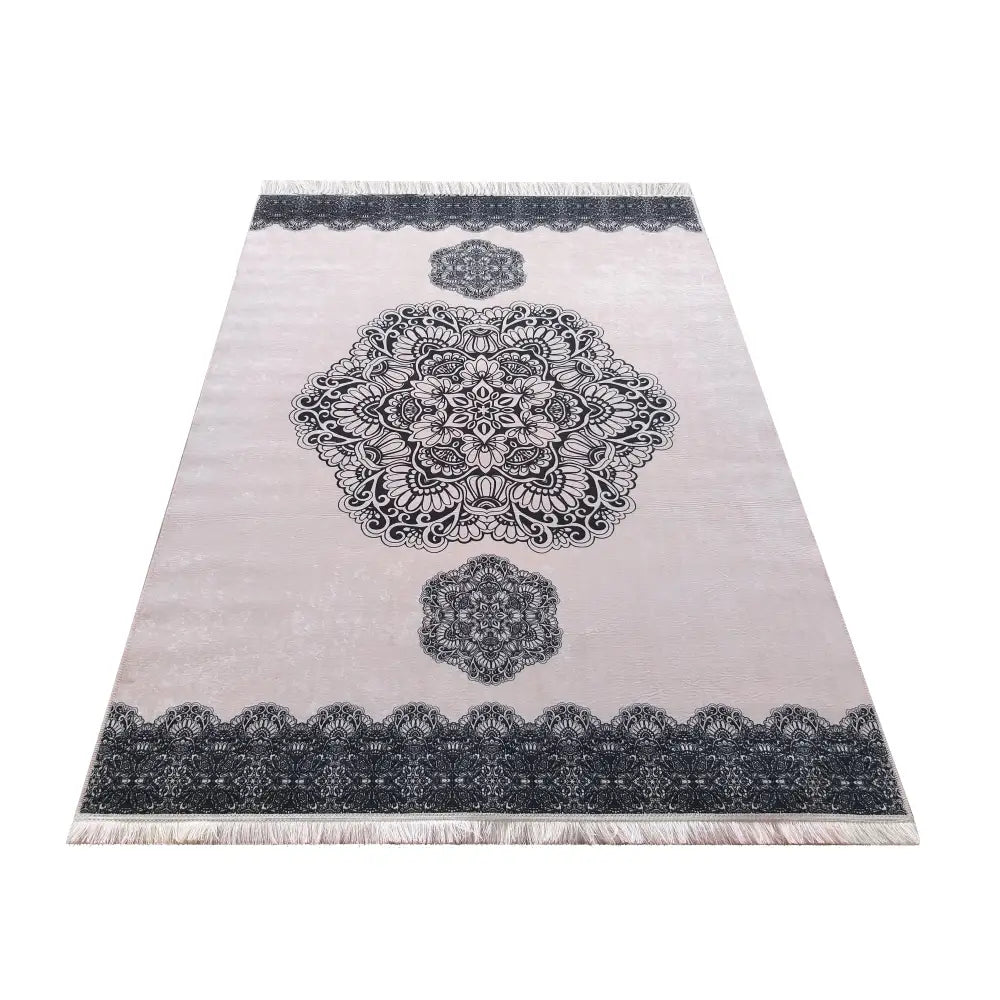 Horeca 10 Pudra teppe, lys base med svarte mønstre og korte frynser, vist fra skrå vinkel ovenfra.