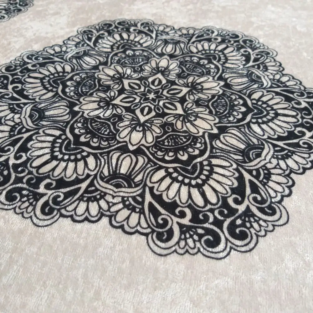 Svart og kremfarget blondemønster med broderte blomster og ornamenter, detalj sett fra skrå vinkel.