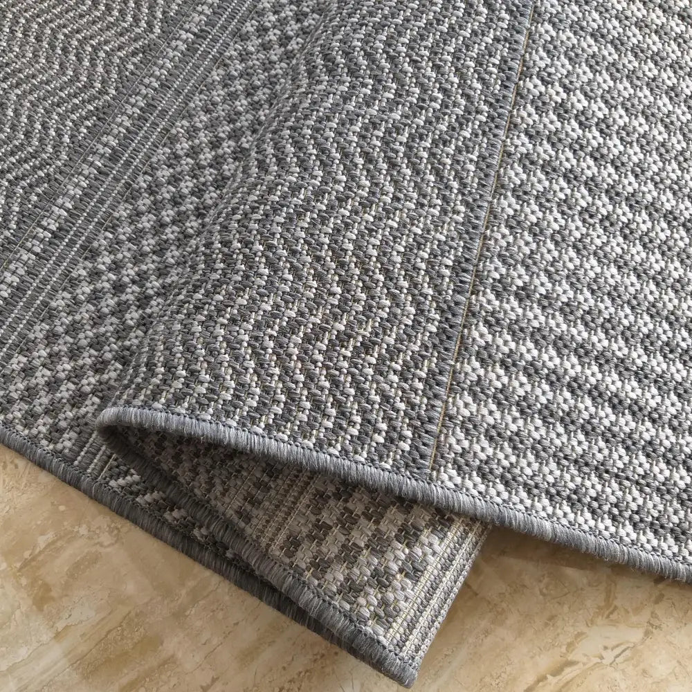 Dobbelsidig grått teppe Zara, nærbilde av grov veving og kontrasterende mønstre på over- og underside.