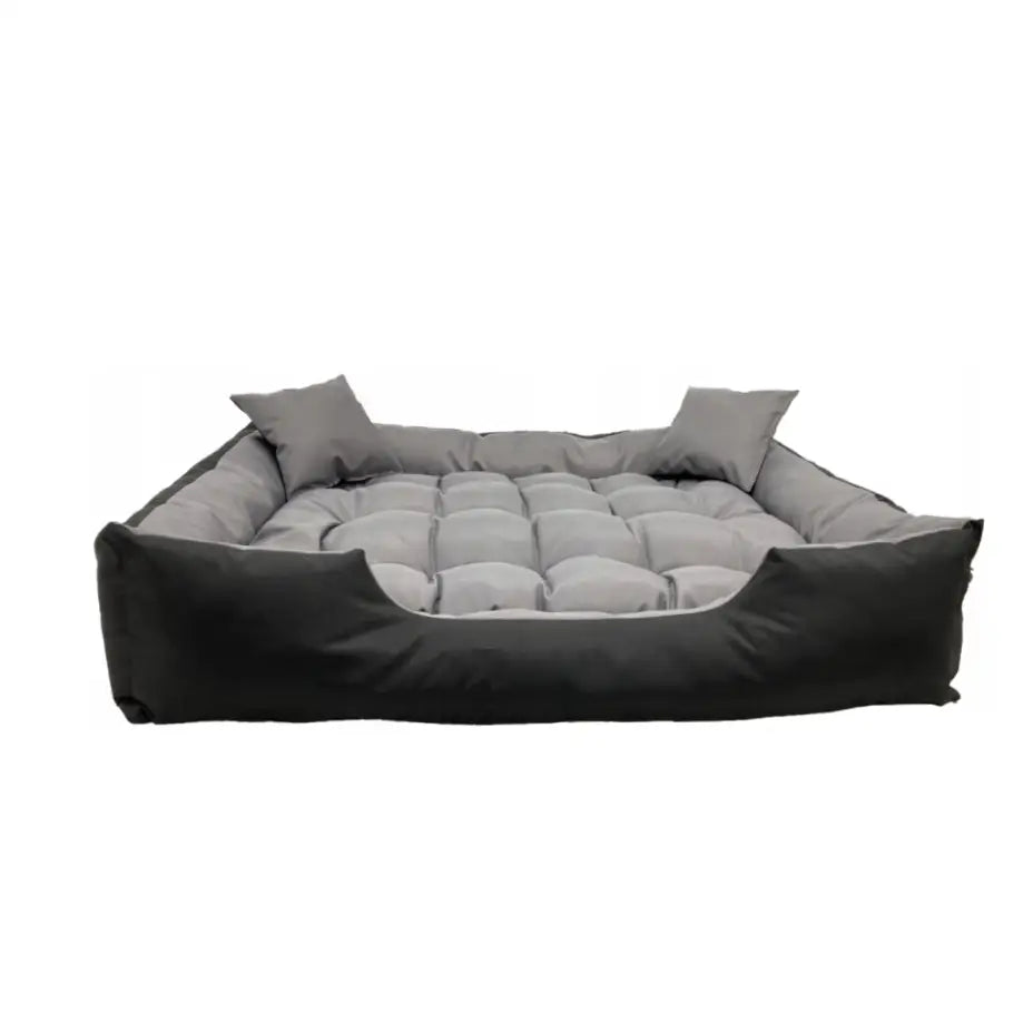 Hundeseng 115x95 i grått, quiltet bunn, høy kant og lav åpning foran, med to løse puter, skrå vinkel.