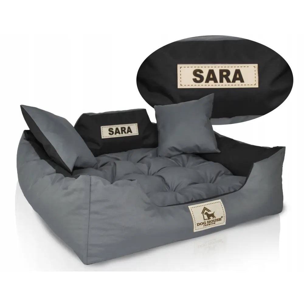 Hundeseng Dog House M i grått og svart med navnelapp "SARA", inkludert to matchende puter, sett skrått forfra.