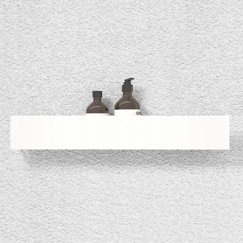 Hvit baderomshylle i stål, 60 cm, montert på lys grå vegg med to brune flasker oppå.