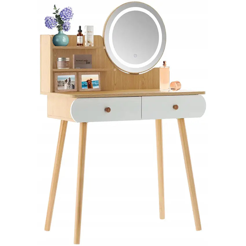 Hvit sminkebord i lyst tre med LED-belyst rundt speil, to skuffer og åpent hylleparti med dekor.