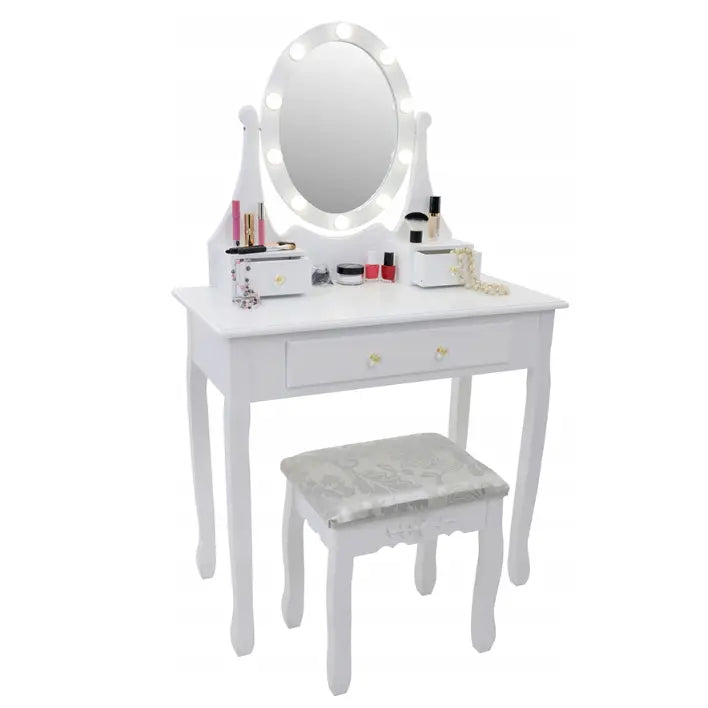 Hvit sminkebord med ovalt LED-speil, skuff og krakk med mønstret pute, sminke og smykker på bordet.