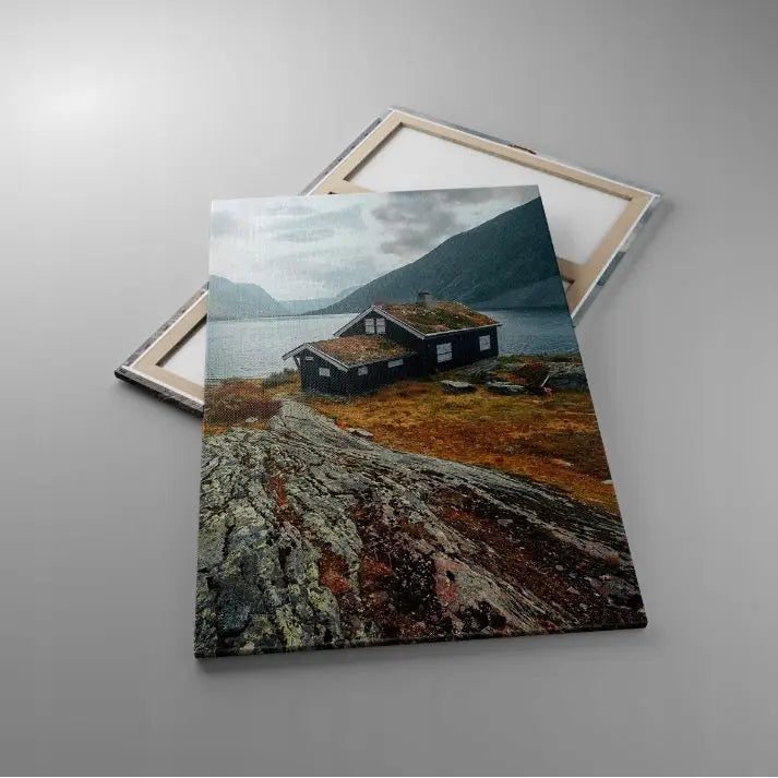 To lerretsbilder med motiv av norsk hytte ved fjord og fjell, fotografert ovenfra mot grå bakgrunn.