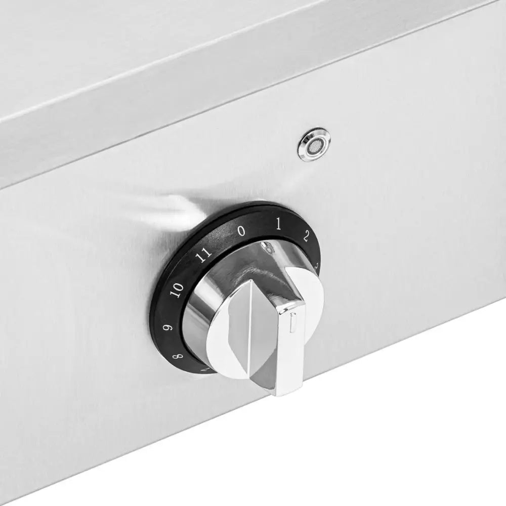 Induksjonskoketopp, nærbilde av roterbar metallbryter med tallskala på børstet ståloverflate.