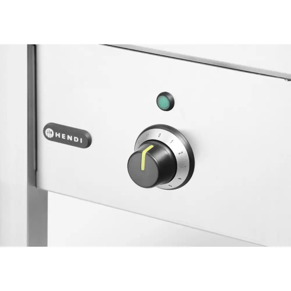 Induksjonstopp, nærbilde av kontrollbryter med tallskala, grønn indikatorlampe og blank metalloverflate.