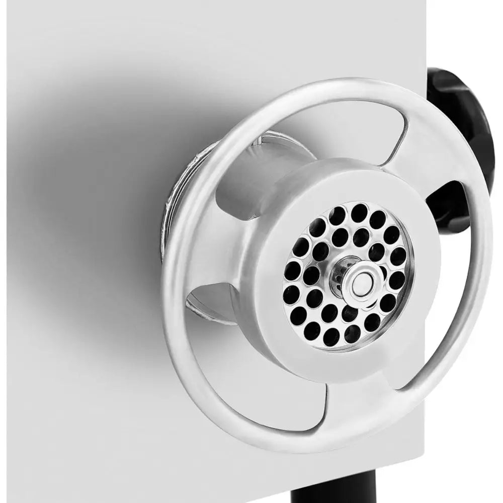 Industriell kjøttkvern, detalj av metallskive med hull og hjulformet håndtak på sølvfarget overflate.